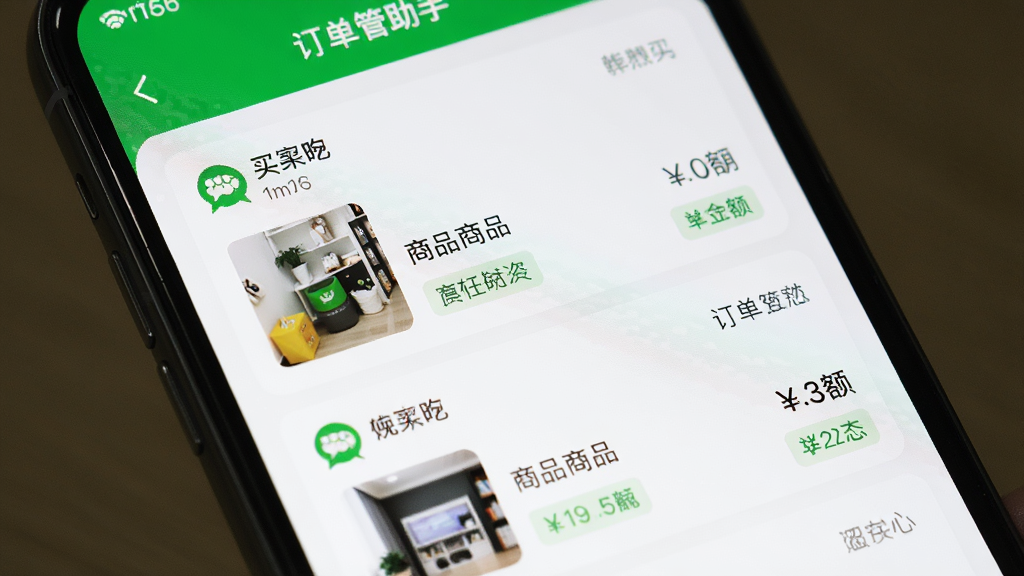 手机屏幕特写,显示微信小店助手的订单管理列表页面,多条订单卡片整齐排列,每条订单显示买家昵称、商品缩略图、金额和状态标签,界面配色以白色和微信绿为主,风格清爽,画质清晰,无多余元素