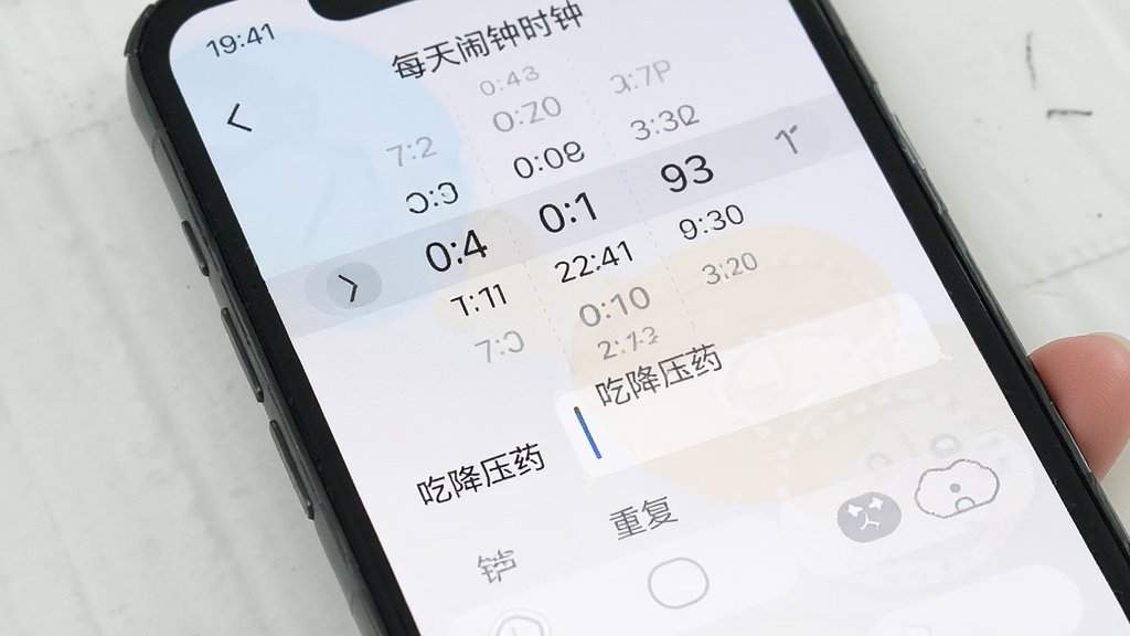 手机屏幕显示“每天闹钟时钟”的闹钟编辑页面,上方是时间选择器,中间有标签输入框写着“吃降压药”,下方是铃声选择和重复选项,界面布局清晰,配色柔和,画质干净,无多余元素