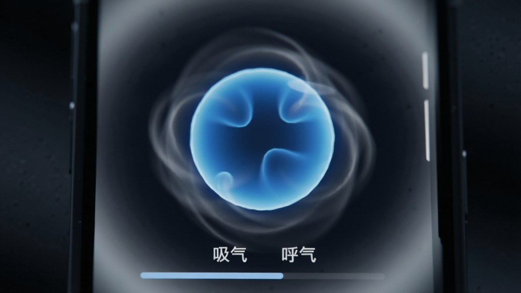 画面主体是一个手机屏幕特写,屏幕上显示着一个正在收缩的蓝色光球,光球周围有淡淡的白色光晕。布局为居中特写,背景是模糊的深色环境,突出屏幕亮度。风格为科技感与宁静感结合,细节包括屏幕下方的