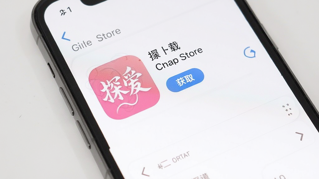 一部iPhone手机屏幕显示“探爱”App Store下载页面,页面中有应用图标、名称和“获取”按钮。背景为浅色,画面简洁,风格干净,无多余元素。