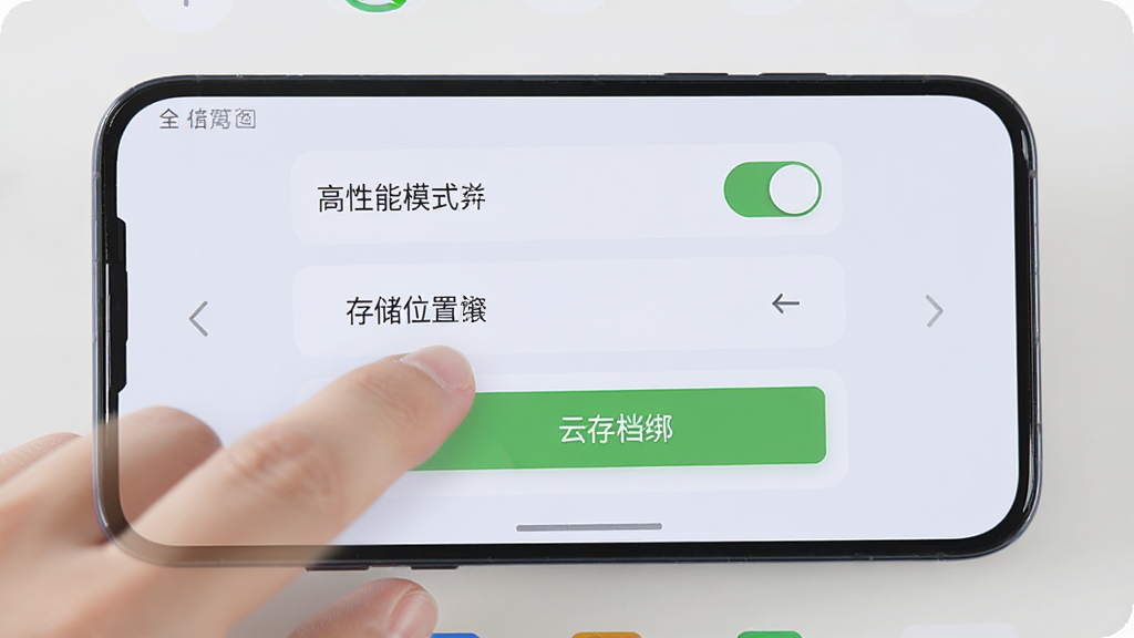 手机屏幕显示游戏设置界面,界面中有“高性能模式”开关、存储位置选择、云存档绑定按钮等选项,旁边有一只手正在点击屏幕,背景为简洁的浅色UI,风格清晰直观,画面干净,高清画质