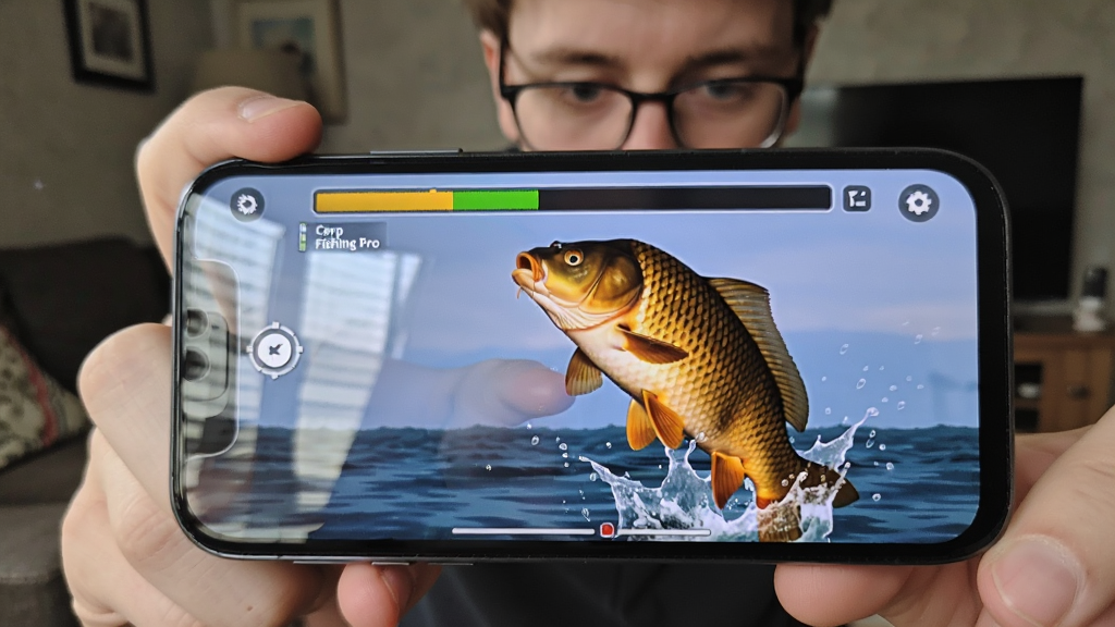 一张手机屏幕截图风格的图片,画面中显示一个玩家正手持手机玩 Carp Fishing Pro,手机屏幕上显示着张力条和一条巨大的鲤鱼跃出水面的特写。布局采用画中画形式,背景是模糊的居家环境。风格为写实生活照,细节包括手机屏幕的反光和玩家专注的表情。画质清晰,干净,无多余文字。