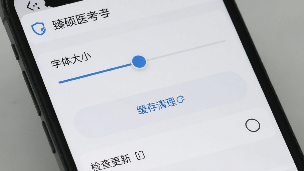 手机屏幕显示“臻硕医考”APP的设置页面,包含字体大小调节滑块、缓存清理按钮和检查更新选项,界面背景为浅灰色,图标简洁,风格清爽,画质干净无多余元素