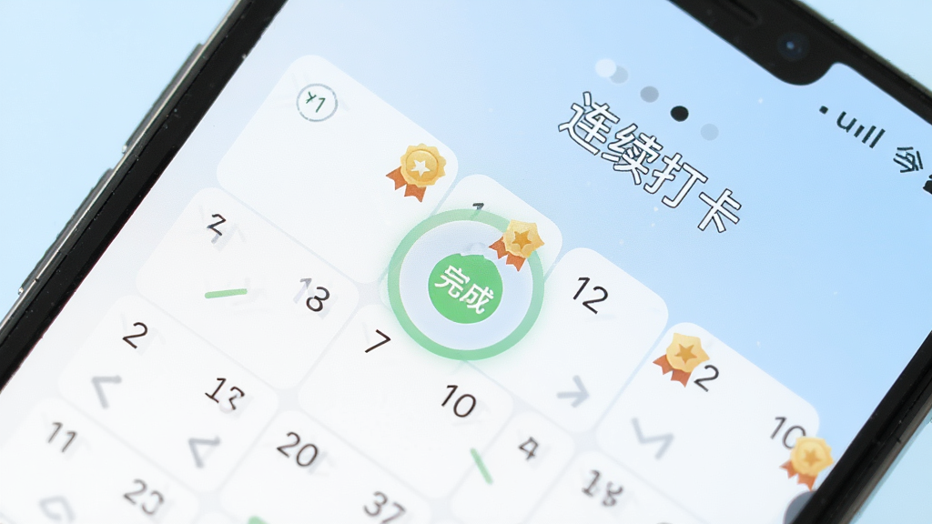 手机屏幕特写显示习惯打卡日历界面,多个日期格被标记为完成状态并带有小徽章图标,旁边有“连续打卡”字样,背景为淡蓝色渐变,界面设计简洁现代,扁平化UI风格,画质清晰锐利,无多余装饰元素