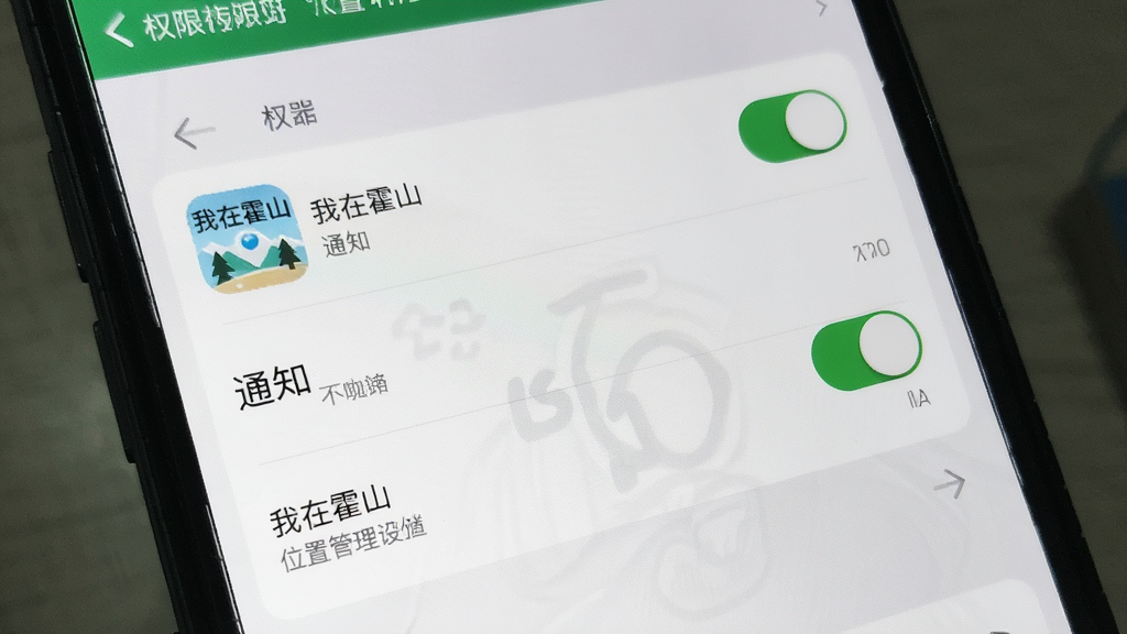 主体为手机屏幕显示权限管理设置界面,布局为竖向列表展示位置存储通知三项权限开关,排版清晰分栏,风格为系统设置写实风,细节包括开关按钮状态与“我在霍山”应用图标,画质干净无多余元素