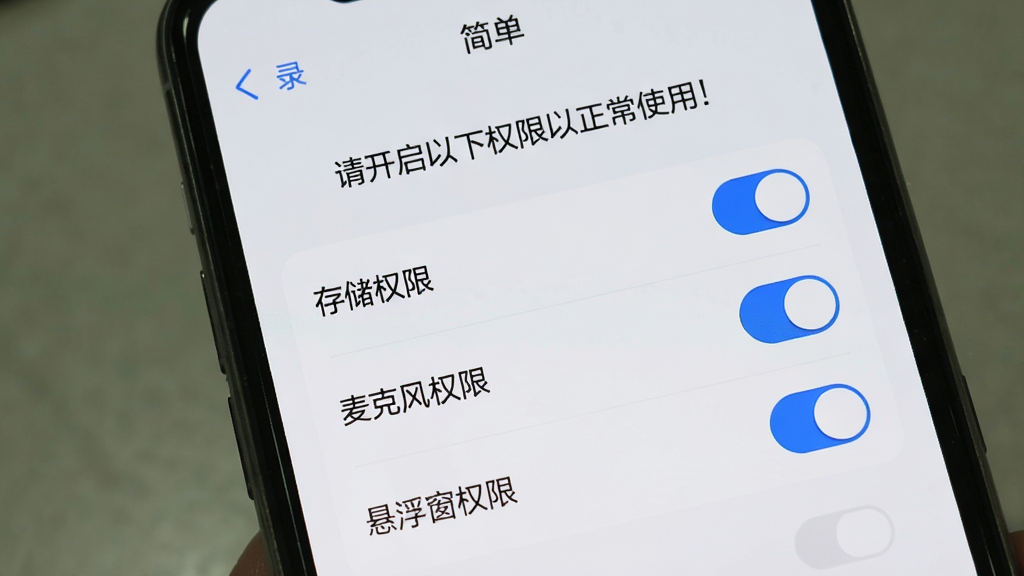 手机屏幕展示“简单录”的权限设置引导页面,页面上列出“存储权限”“麦克风权限”“悬浮窗权限”三个选项,每个选项右侧有开关按钮,页面顶部有“请开启以下权限以正常使用”的提示文字,界面风格简洁,浅色背景配蓝色开关,画质清晰