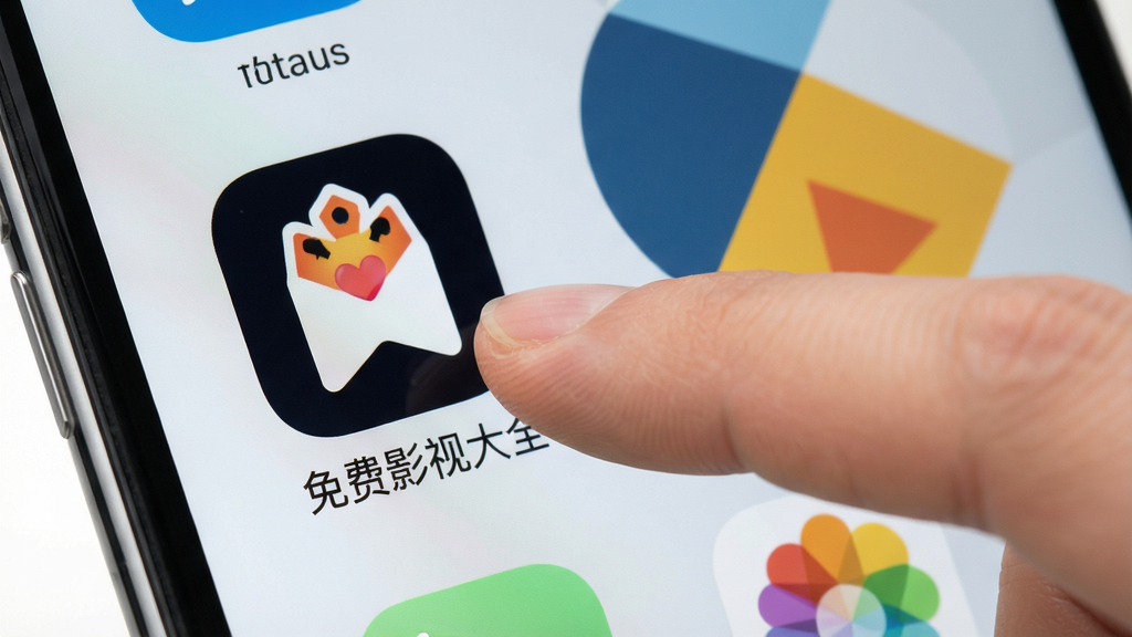 一幅手机操作示意图,主体为手指点击“免费影视大全”App图标,背景为手机桌面,桌面壁纸为简约几何图案,风格写实,画质干净,无多余元素。