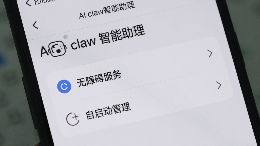 手机屏幕上显示“AI claw智能助理”的设置页面,突出显示“无障碍服务”和“自启动管理”选项,背景为浅灰色,界面清晰,文字可读性强,画质干净