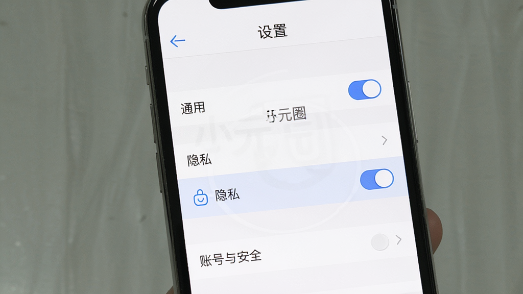 主体:一部智能手机显示“小元圈”应用的设置页面,包含“通用”、“隐私”、“账号与安全”等选项。布局:手机竖屏居中,设置列表清晰可见,部分选项右侧有开关按钮。排版:列表式布局,每个选项间隔均匀,顶部有返回箭头和“设置”标题。风格:简洁实用,符合系统设置界面风格,背景为白色。细节:屏幕中显示“小元圈”字样,其中“隐私”选项高亮,周围有辅助图标,整体画面干净。画质:高清,真实感强,无多余元素。