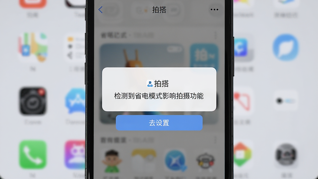 主体:一张手机截图,展示“拍搭”应用在省电模式下的警告提示。布局:手机屏幕居中,背景为桌面,提示框内文字清晰。排版:竖屏展示,下方有“去设置”按钮。风格:写实风格,界面简洁。细节:提示框内包含“拍搭”名称,文字内容为“检测到省电模式影响拍摄功能”。画质:高清,干净,无多余元素。