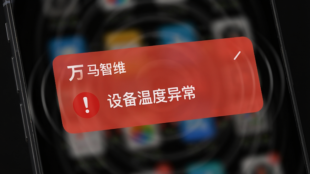 手机屏幕弹出“万马智维”的红色预警通知卡片,卡片上有一个感叹号图标和“设备温度异常”字样。手机背景为深色模式界面,周围有微弱的震动波纹效果,风格现代科技,画面干净,高清画质。