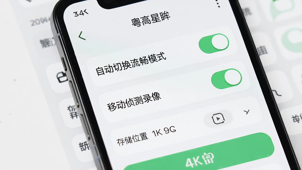 手机屏幕展示“粤高星眸”设置页面,页面中包含“自动切换流畅模式”开关、“移动侦测录像”开关、存储位置选择等选项。界面采用浅色背景与绿色高亮按钮,布局清晰,风格实用简洁,细节到位,4K画质,干净无多余元素。