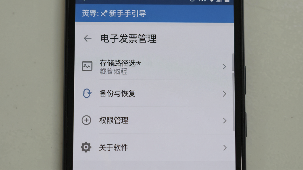 一部安卓手机屏幕显示“电子发票管理”的设置页面,页面中包含存储路径选择、备份与恢复、权限管理、关于软件等选项,屏幕上方有“新手引导”提示条,背景为淡灰色,界面风格朴素实用,图标线条简洁,画质清晰,无多余装饰元素