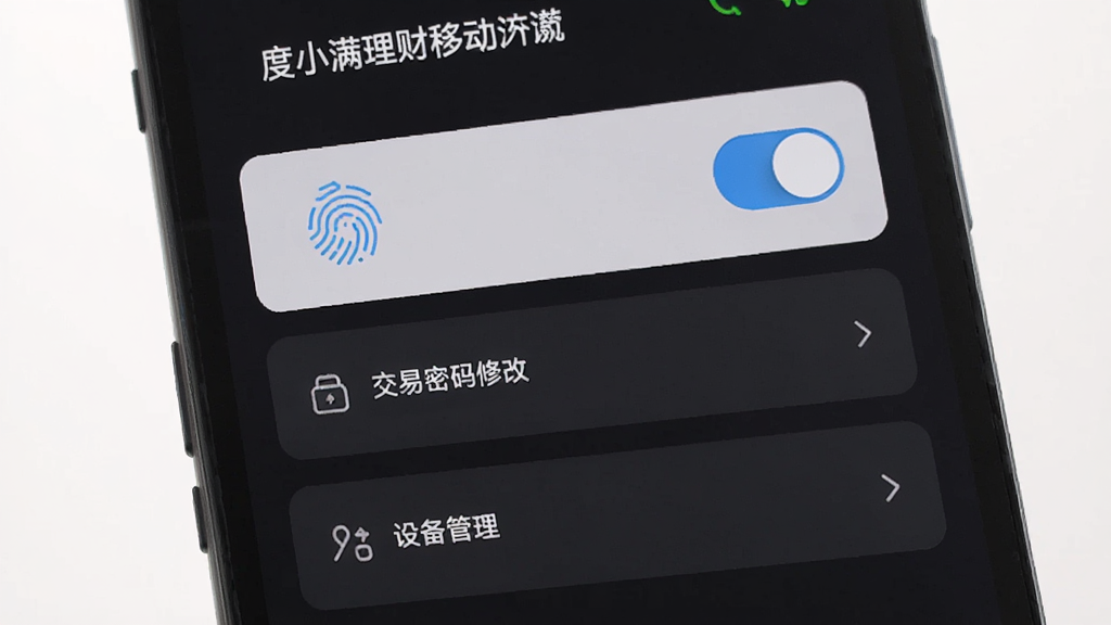 一张展示度小满理财移动端安全设置页面的图片,画面中手机屏幕显示指纹解锁开关、交易密码修改、设备管理等选项,背景为深色护眼模式,风格简约沉稳,细节清晰,画质干净,无多余元素
