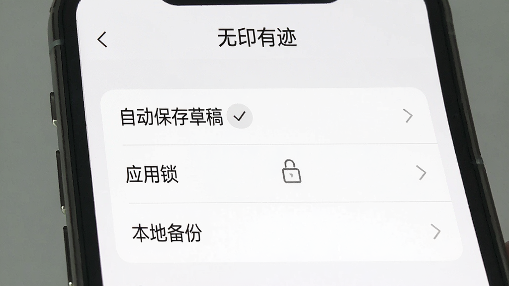 一张手机界面操作示意图,画面中展示“无印有迹”的设置页面,页面中有“自动保存草稿”“应用锁”“本地备份”等选项,界面风格为浅色极简,布局清晰,文字可读,画质干净,无多余元素