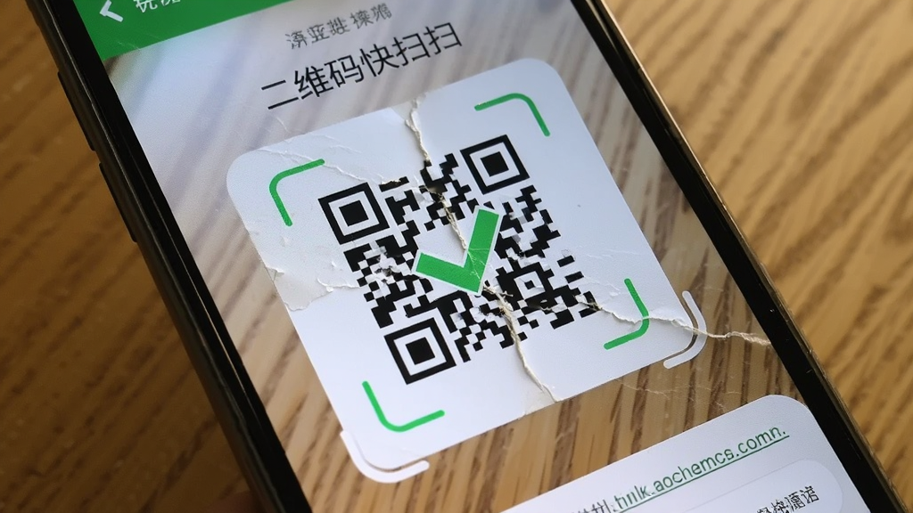 一个手机镜头对准一张带有轻微折痕的二维码卡片,手机屏幕显示识别成功的绿色对勾和链接预览,背景为木质桌面,光线柔和,画面风格写实,突出