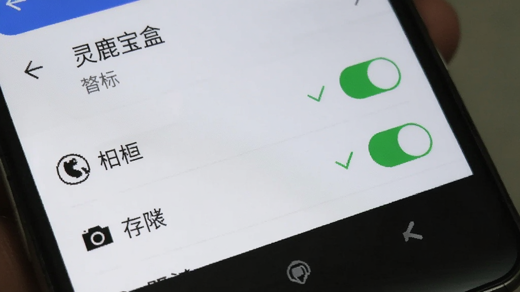一部安卓手机屏幕显示“灵鹿宝盒”APP的权限设置页面,画面中相机和存储权限开关处于开启状态,旁边有绿色对勾标识,背景为手机系统设置界面,风格简洁,画质清晰,无多余元素