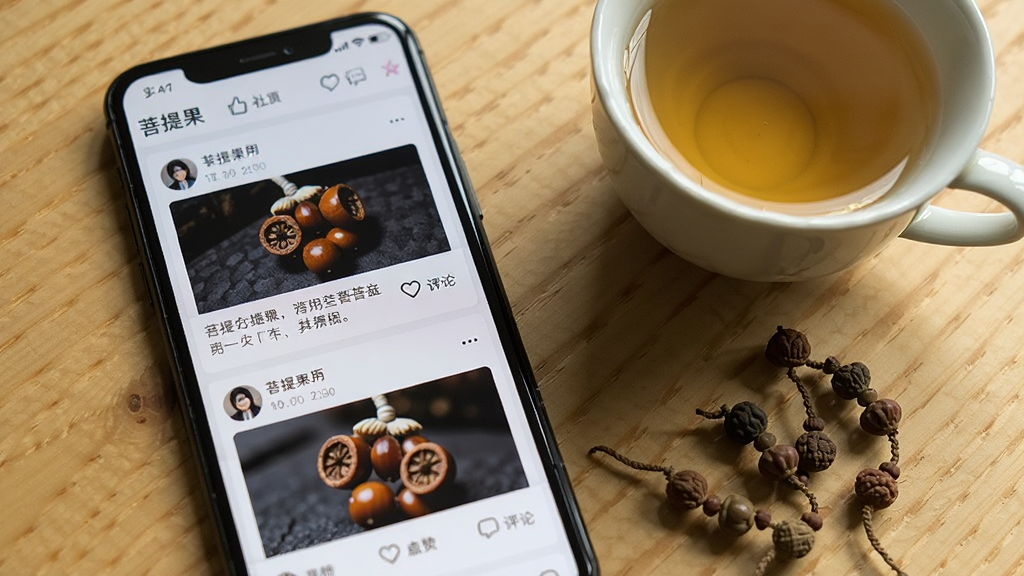 一部手机屏幕显示“菩提果”App的社区页面,页面内有多条用户发布的菩提子图文帖子,每条帖子包含用户头像、昵称、菩提子照片和文字描述,下方有点赞和评论图标,手机旁边放着一杯茶和几颗菩提子散珠,背景是木质桌面,整体风格生活化,光线自然,画质清晰,干净无多余元素。