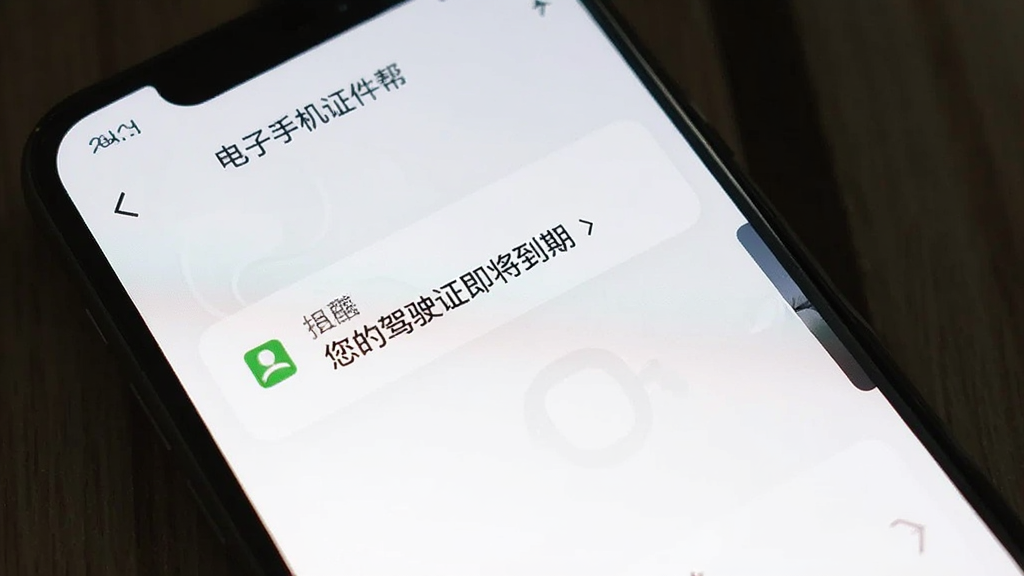 手机屏幕显示电子手机证件帮的到期提醒界面,画面中有一条通知提醒“您的驾驶证即将到期”,背景为白色,界面简洁清晰,画质干净,图片中文字为“电子手机证件帮”