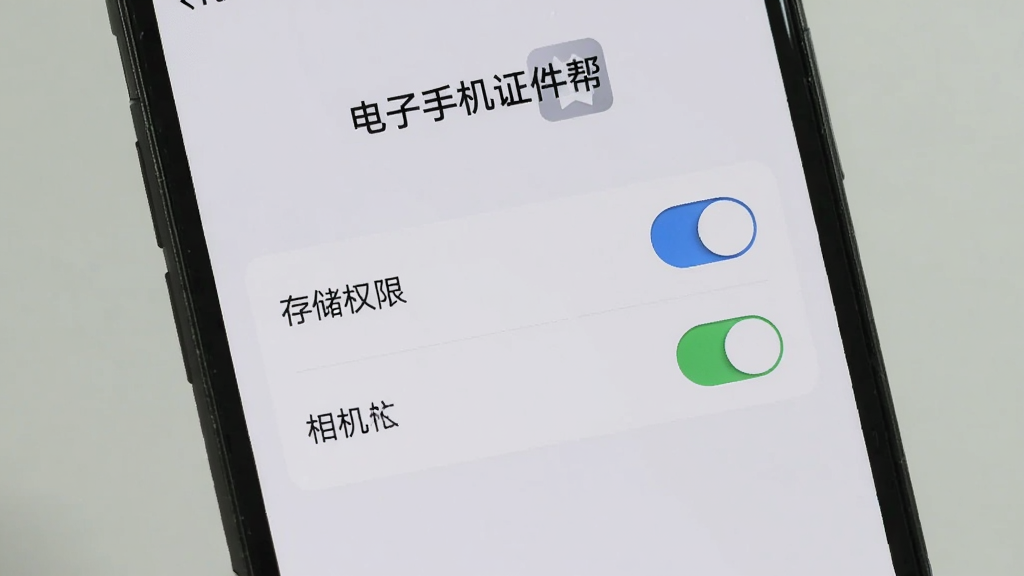 一部手机展示电子手机证件帮的安装权限设置界面,画面中有存储权限和相机权限的开关按钮,背景为浅灰色,界面简洁明了,画质清晰,图片中文字为“电子手机证件帮”