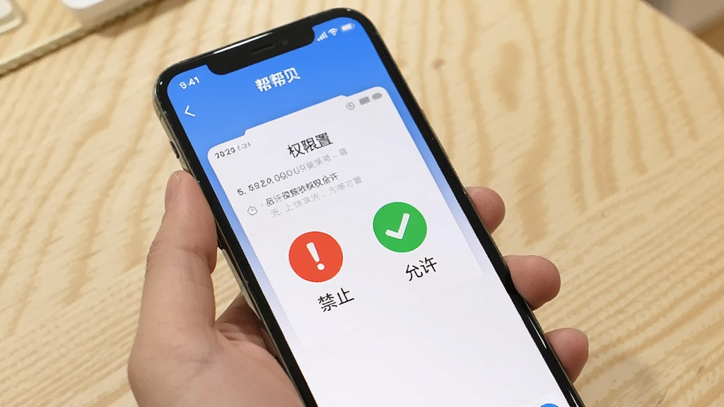 一张手机操作示意图,画面中一只手拿着手机,手机屏幕显示“帮帮贝”应用的权限设置界面,旁边有红色感叹号和绿色对勾图标分别表示禁止和允许,背景为浅色木纹桌面,风格生活化,画质清晰干净
