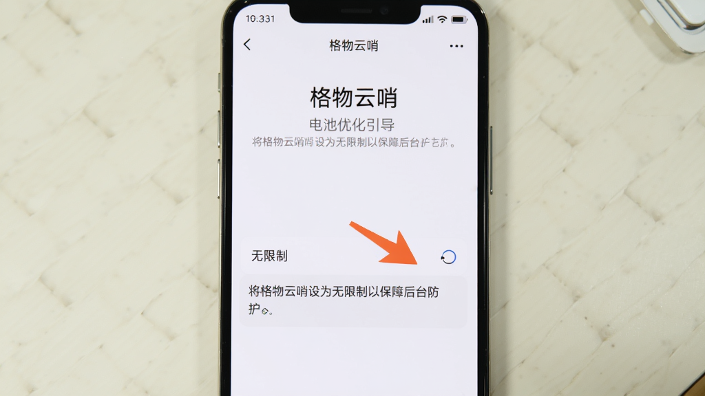 手机屏幕显示“格物云哨”的电池优化设置引导页面,页面中有箭头指向“无限制”选项,并配有文字说明“将格物云哨设为无限制以保障后台防护”。手机背景为简洁的浅色桌面,整体风格为教程示意图,画质清晰,排版直观,无多余元素。