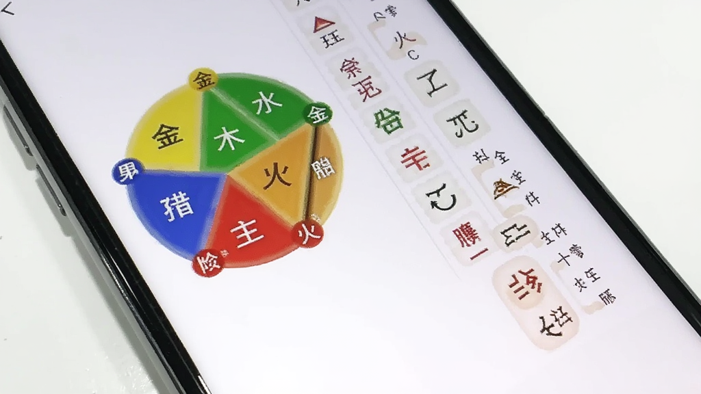 一张展示在雪八字排盘五行分析图表的手机截图,画面中手机屏幕显示着圆形的五行分布图,用红绿蓝黄黑五种颜色代表金木水火土,旁边配有十神列表,背景为干净的白色桌面,风格现代简洁,画质清晰,干净无多余元素。