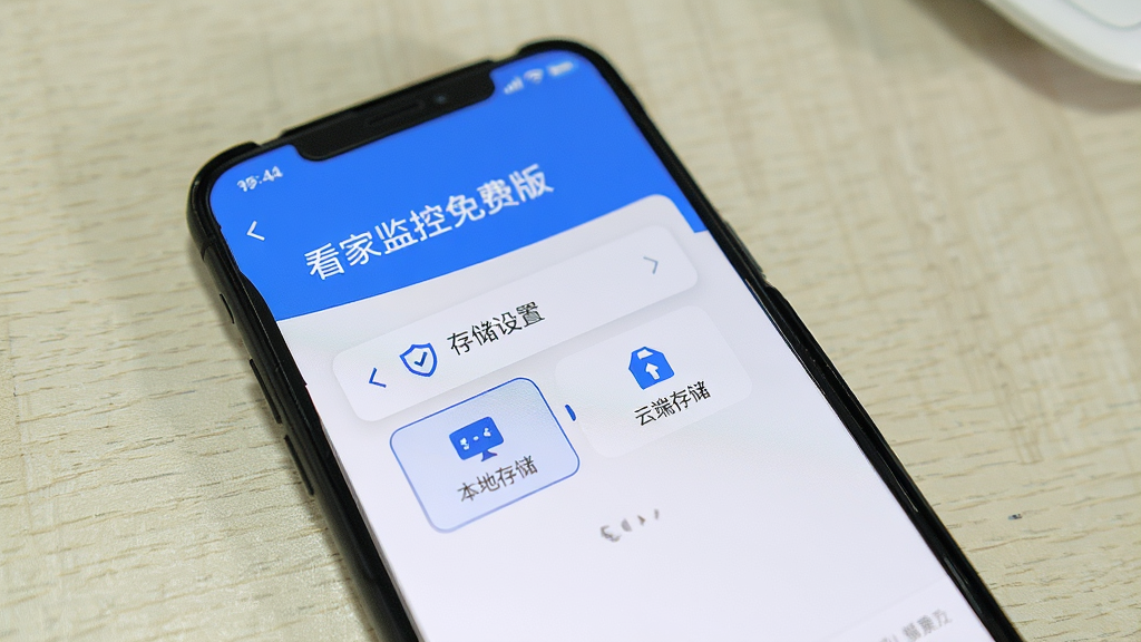 手机屏幕显示“看家监控免费版”的存储设置界面,有本地存储与云端存储两个选项,界面简洁,背景为浅色桌面,写实风格,画质干净,无多余元素