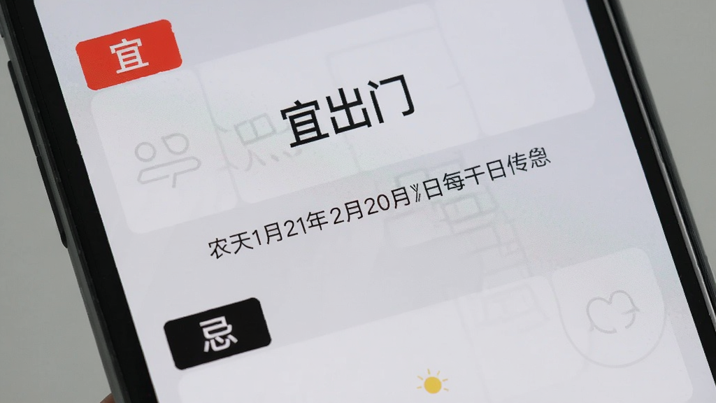 手机屏幕特写,显示“宜出门”应用的每日宜忌页面,上半部分用红色标注“宜”事项,下半部分用黑色标注“忌”事项,中间有农历日期和干支信息,背景为浅灰色,布局规整,文字清晰,风格简洁,画质干净