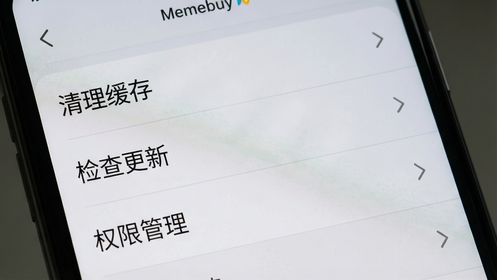 一张展示Memebuy应用设置页面的手机截图,画面中手机屏幕显示设置菜单,包含“清理缓存”“检查更新”“权限管理”等选项,排版为列表式,风格为浅灰质感,细节上每个选项右侧有箭头图标,画质高清,干净,无多余元素