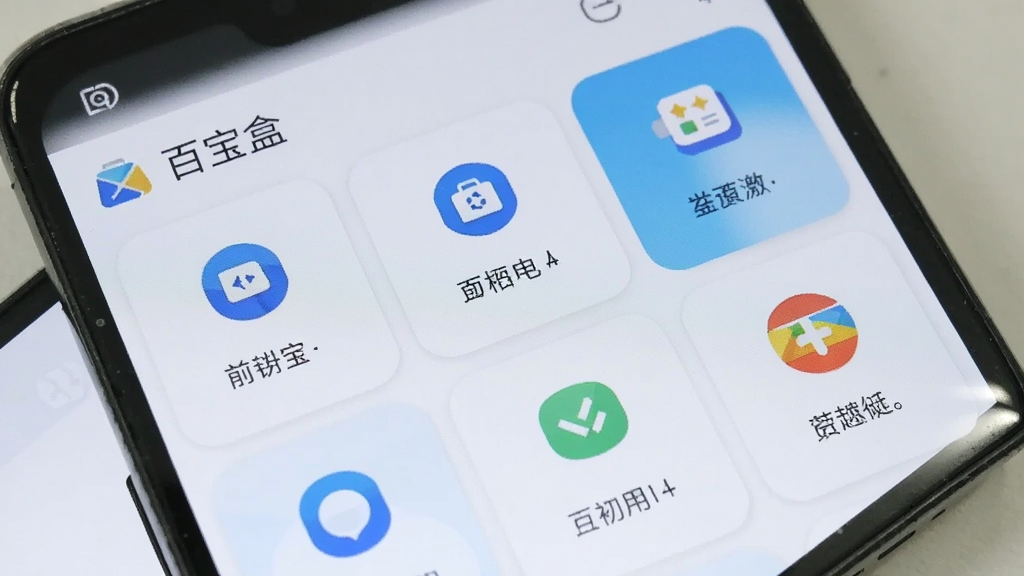 一部安卓手机屏幕特写,画面中百宝盒应用界面展示了多个功能卡片以网格形式排列,每个卡片带有不同的功能图标和简要文字说明,界面风格清爽简约,主色调为白色和淡蓝色,顶部显示