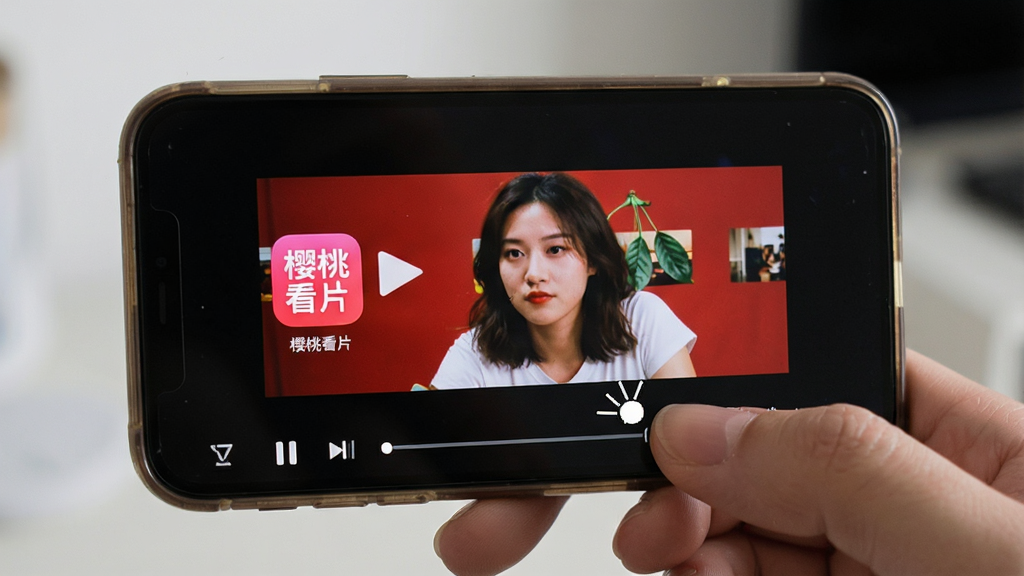 一张展示“樱桃看片”在手机上安装运行并正常播放视频的实拍风格图,主体为手持智能手机,屏幕显示樱桃看片播放界面,布局包含手机边框与手指操作指示,风格为真实使用场景摄影,细节包含清晰的播放画面与“樱桃看片”应用图标,画质高清,画面干净,无多余元素